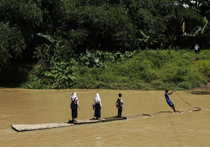 Študenti prečkajo reko na bambusovem splavu na poti iz šole. Indonezija, provinca Banten. | Foto: Reuters