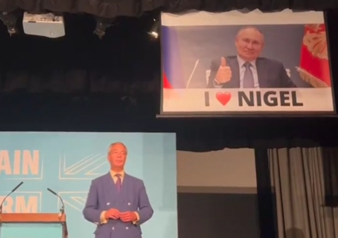 Nigel Farage tu še ni opazil, da se je za njegov hrbet prikradel Vladimir Putin, so pa to opazili obiskovalci dogodka stranke Reform UK. | Foto: posnetek zaslona