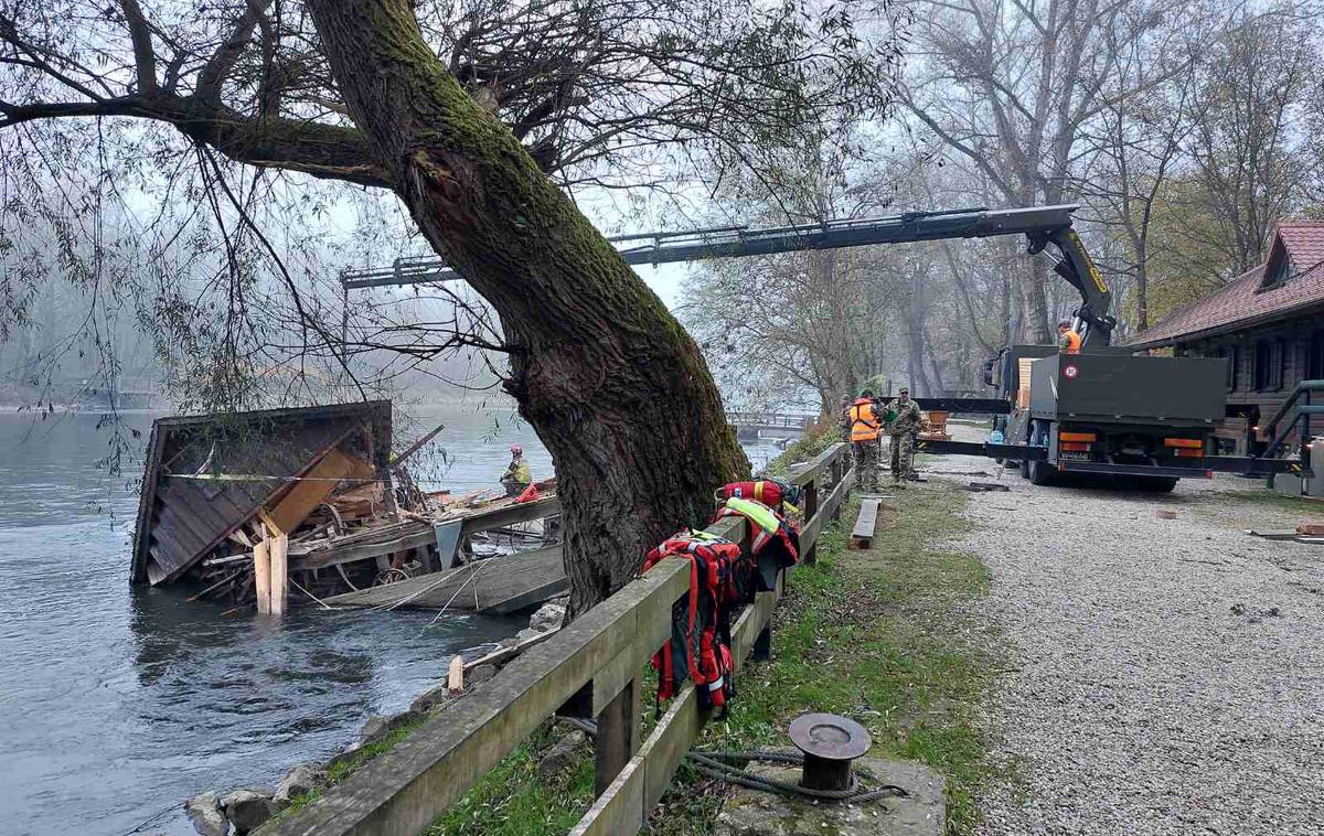 Slovenska vojska, mlin na Muri | Mlin, ki je ena najbolj obiskanih turističnih točk v Pomurju, se je začel potapljati konec septembra, takrat so iz manjšega čolna vsake tri ure izčrpali vodo. Na začetku oktobra so ga poskusili dvigniti z reke, vendar se je pri dvigovanju večjega čolna s hišico in mlevnim sistemom polomil tram, na katerega je bila pripeta veriga, mlin je zgrmel nazaj v reko Muro ter se sesul sam vase. | Foto ZTKS Beltinci