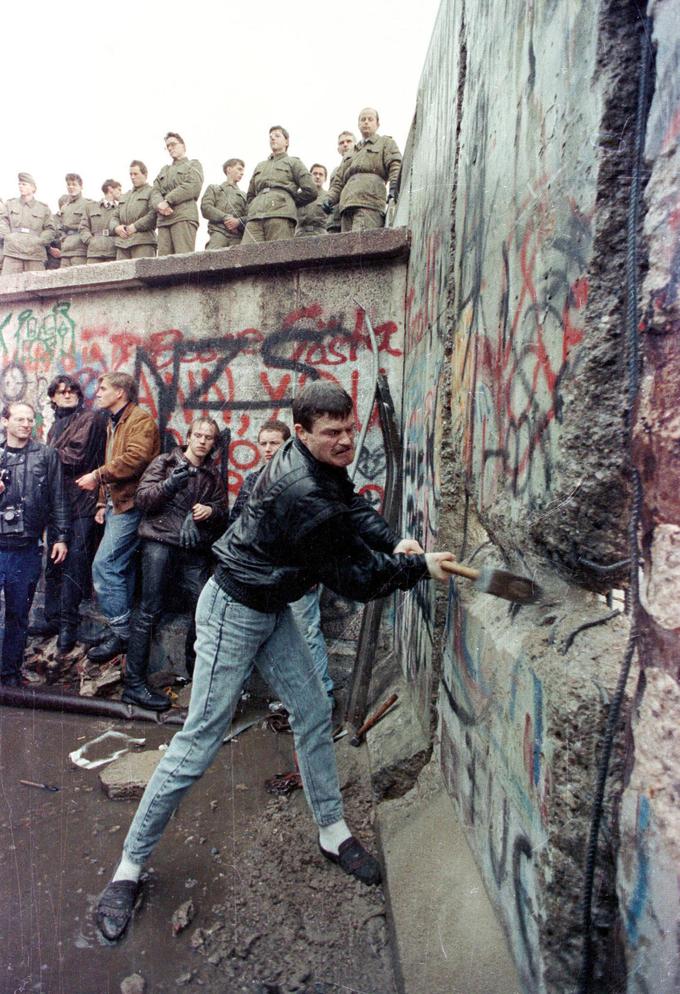 Protestnik poskuša uničiti Berlinski zid. Dogajanje opazujejo pripadniki vzhodnonemške obmejne vojske. | Foto: Reuters
