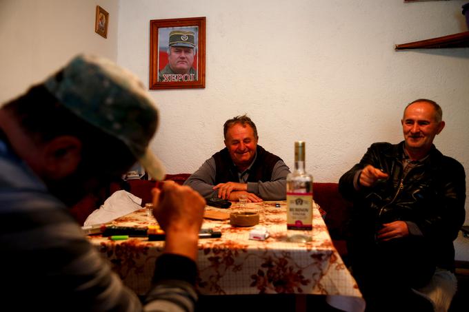 Duško Mladić (v sredini), bratranec Ratka Mladića, s svojima bratoma pije v zasilni kavarnici. "Ni ubijal ljudi. Med vojno je zbral naše muslimanske sosede iz bližnje vasi in jih posvaril, da je čas, da gredo," pravi Duško, ki sedi pod portretom bratranca, na katerem piše heroj. | Foto: Reuters