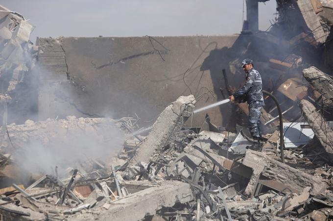 Sirski gasilec se bori z ognjenimi zublji med ruševinami raziskovalnega centra v bližini Damaska, ki ga je zadela ameriška raketa.  | Foto: Reuters