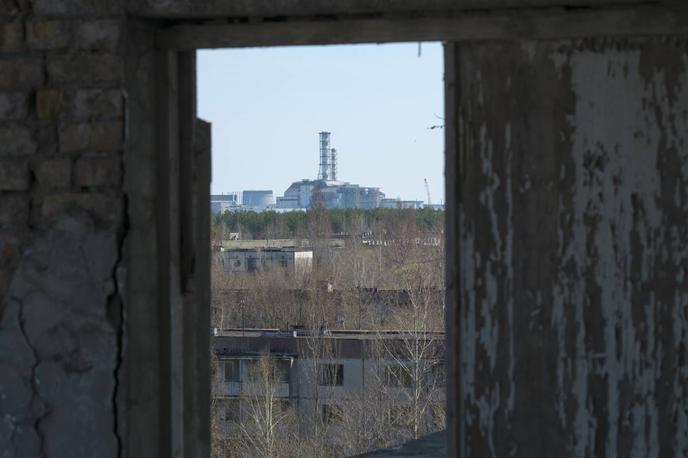 Černobil, Pripjat | Černobilska jedrska elektrarna skozi okno enega od blokov v zapuščenem mestu Pripjat. Fotografija je bila posneta še pred začetkom gradnje nove zaščitne kupole, s katero so leta 2017 prekrili še vedno sevajoči del elektrarne. | Foto Reuters