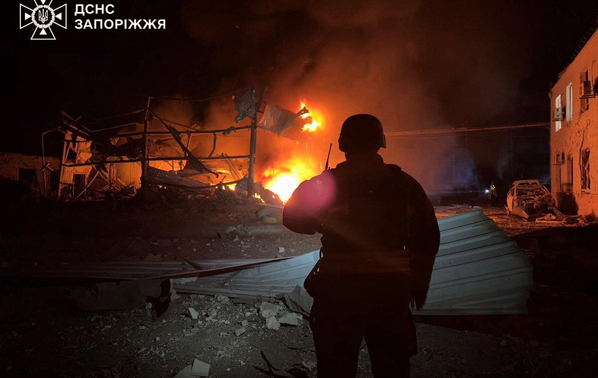 Rusija napad Ukrajina | Pogled proti goreči stavbi po nočnem napadu v Zaporožju. | Foto Reuters