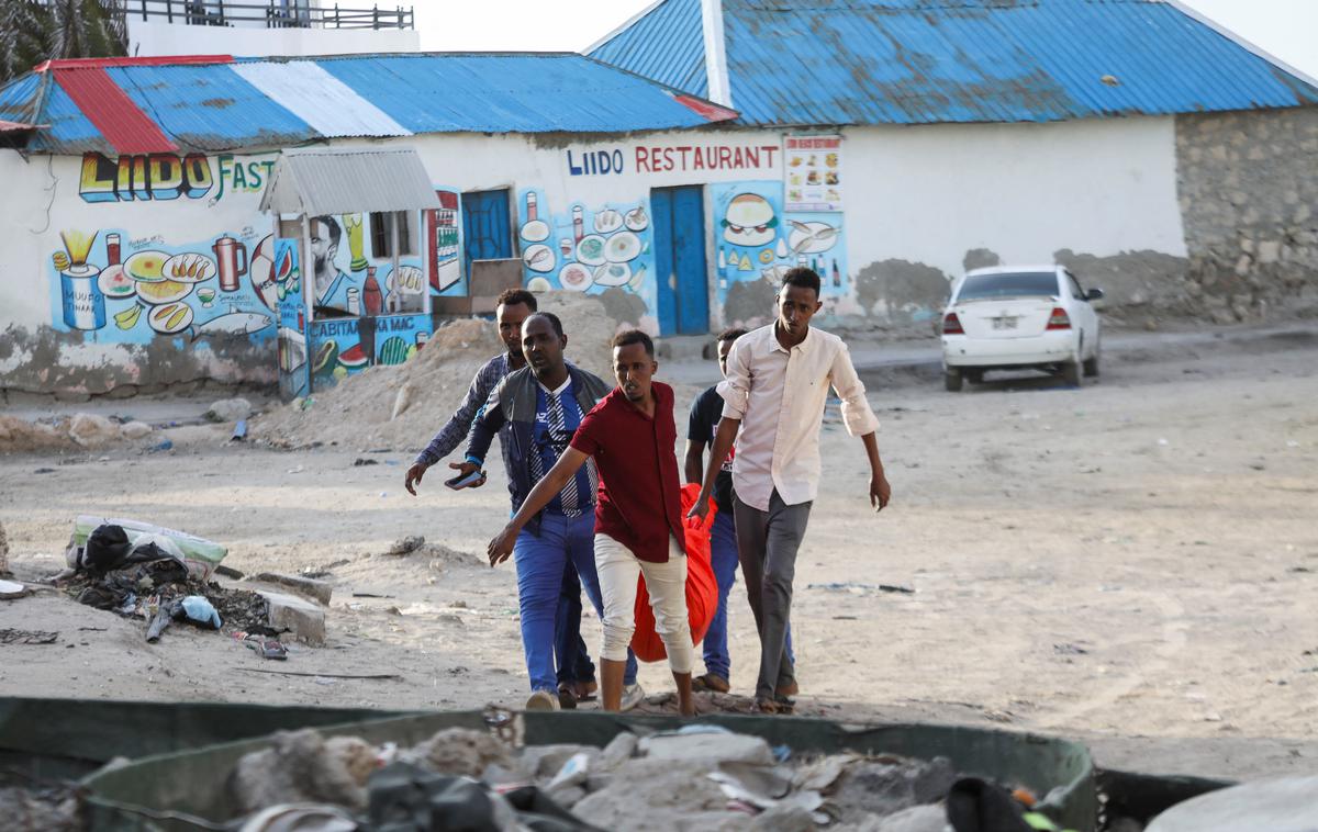 napad v Mogadišu | Moški nesejo truplo ženske, ubite v napadu skrajne islamistične skupine Al Šabab, na plažo Lido v Mogadišu.  | Foto Reuters
