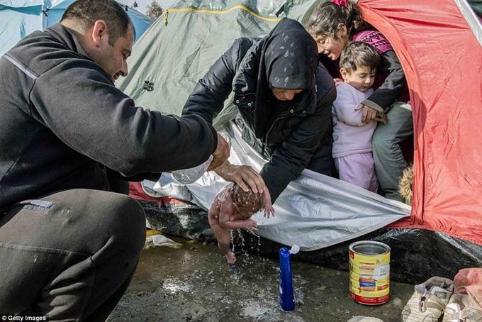 Nekaj ur starega dojenčka so umili kar v luži pred šotorom. | Foto: 