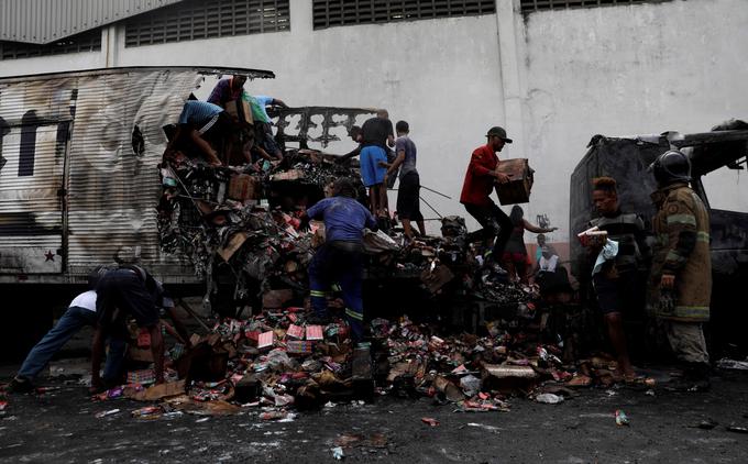 Prebivalci favel med ropanjem tovornjaka, ki je zgorel v spopadu med tolpami. | Foto: Reuters