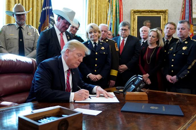 Donald Trump | Ameriški predsednik Donald Trump se je v Ovalni pisarni Bele hiše ob podpisu veta obkrožil z možmi v uniformah in starši otrok, ki so jih umorili nezakoniti priseljenci. | Foto Reuters