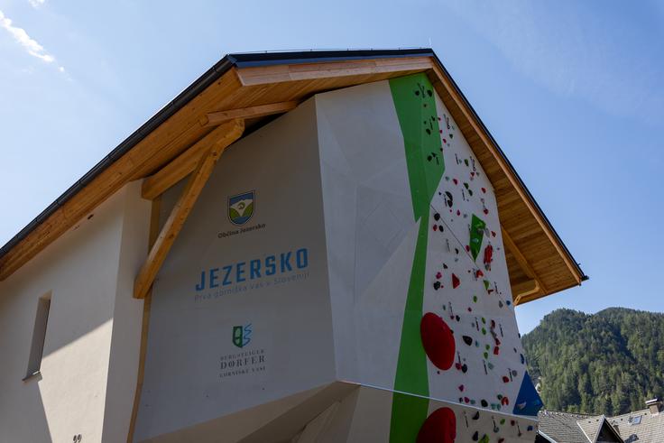 Plezalna stena na prenovljeni šoli v vasi Zgornje Jezersko. In napis, s katerim ponosno sporočajo, da so del mednarodne mreže gorniških vasi. | Foto: Matej Podgoršek
