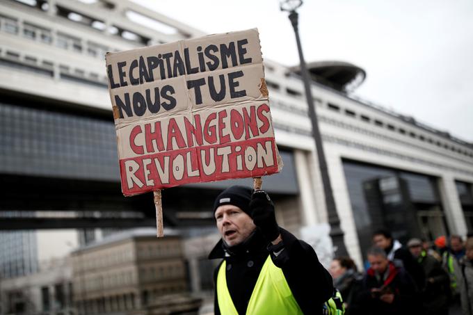 V letih 2018 in 2019 je Francija doživela množične proteste rumenih jopičev. Na fotografiji: protestnik v rumenem jopiču nosi napis, ki se v slovenščini glasi: kapitalizem nas ubija – spremenimo se – revolucija. Da bi vzel veter iz jader protestnikom, je Macron obljubil številne spremembe, med drugim tudi ukinitev ENA. | Foto: Reuters